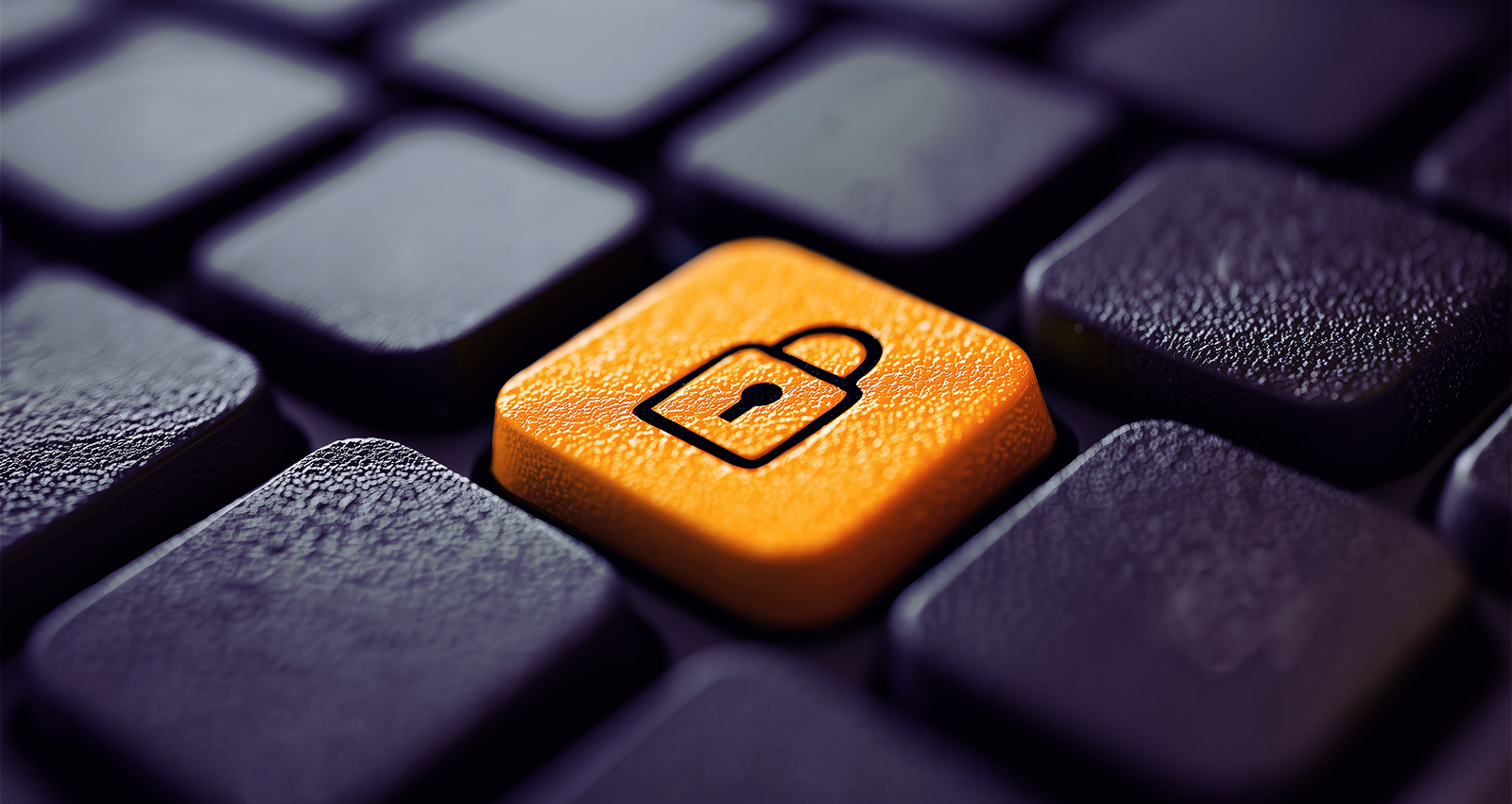 Imagem de um teclado de computador com uma tecla laranja de segurança ativada com um cadeado. Tema relacionado a proteção de informações digitais, privacidade e crimes cibernéticos.