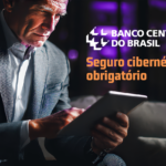 Homem de terno usando tablet em ambiente moderno com destaque para o banco central do Brasil e o tema de seguro cibernético obrigatório pelo Banco Central.